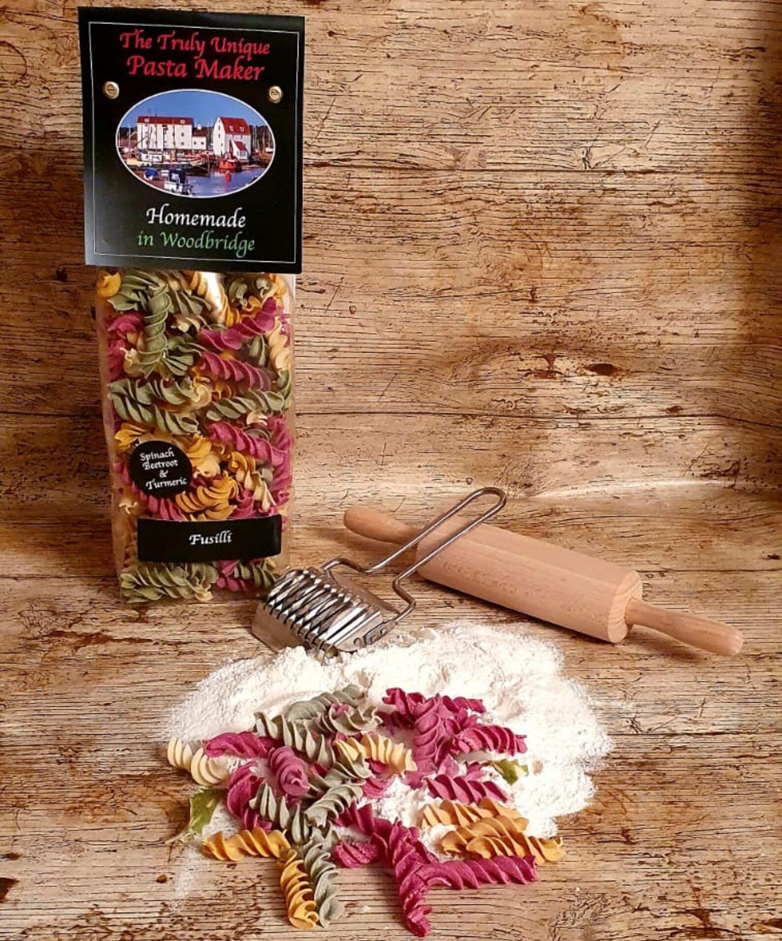 bag of pasta displayed with flour, rolling pin and loose pasta on table